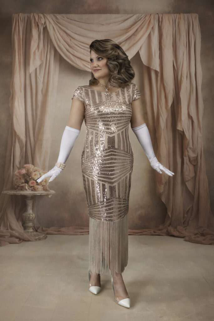 Pink flapper dress on a beautiful woman posed infant of pink curtains and a table of flowers